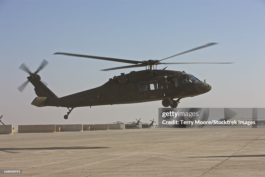 A UH-60 Black Hawk helicopter landing at a military base in Iraq.