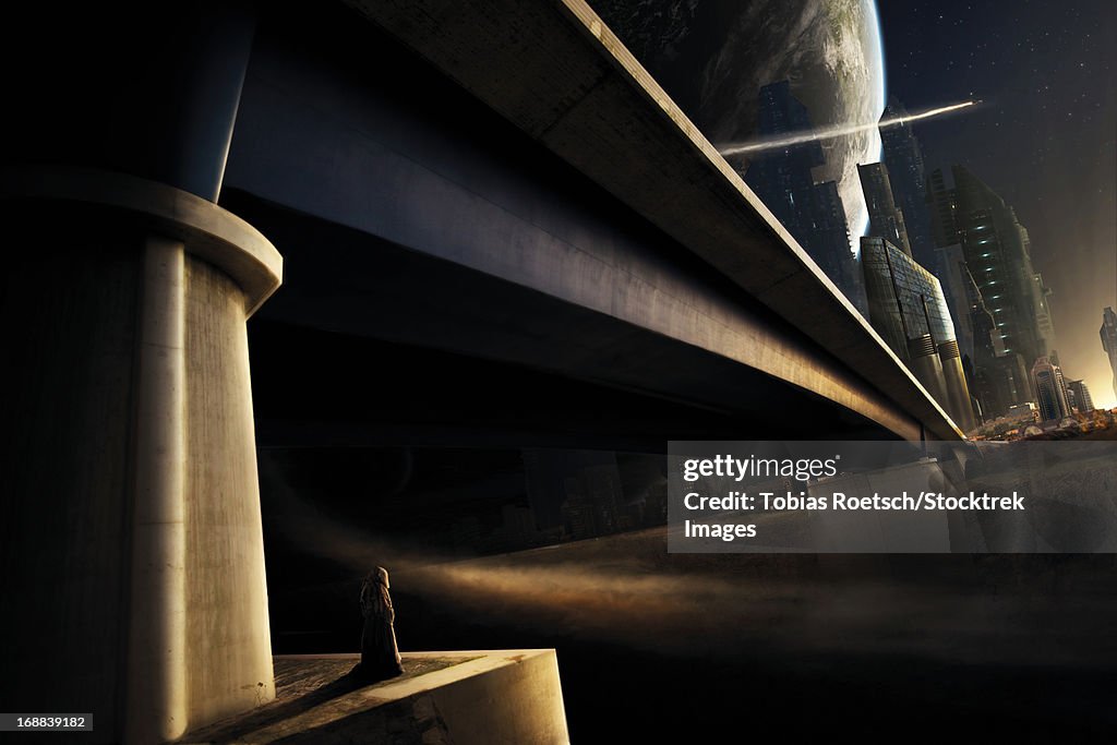 A banned person looks back to his old hometown from under a bridge.