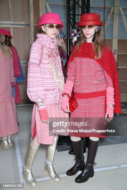 Backstage at the Chanel show during Paris Fashion Week Autumn/Winter 2016/17, two models wear classic tweed skirt suits in pink and red check with...