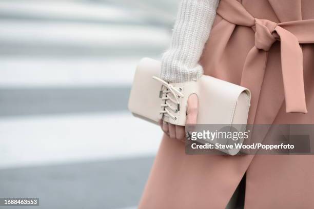 At the Christian Dior show during Paris Fashion Week Autumn/Winter 2016/17, close up of a woman holding a cream leather clutch bag and matching laced...