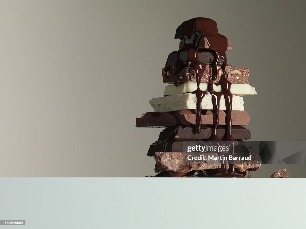 Chocolate syrup dripping over stack of chocolate bars