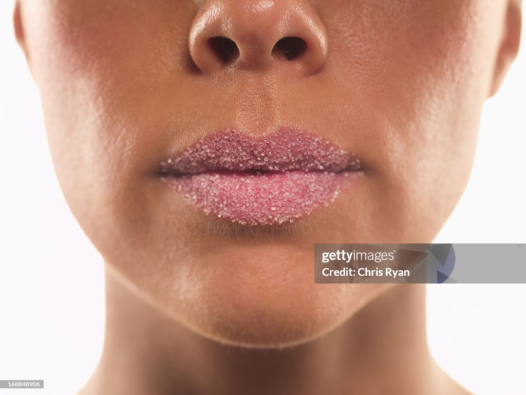 Close up of sugar covering lips of woman with pink lipstick