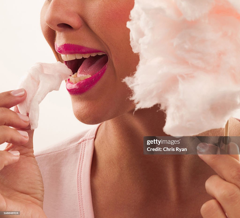 Woman with pink lipstick eating cotton candy