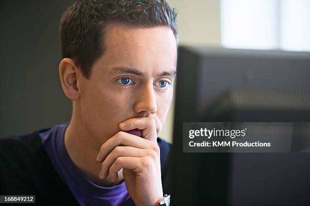 man using computer at desk - mano tapando la boca fotografías e imágenes de stock
