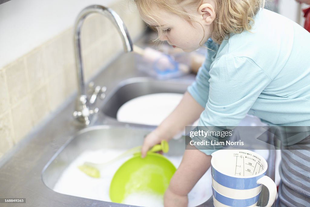 Girl washing dishes in kitchen