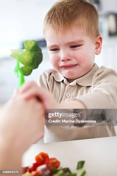 crying boy refusing broccoli in kitchen - broccoli white background stock pictures, royalty-free photos & images