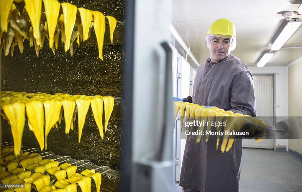 Worker inspecting smoked haddock fillets in food factory