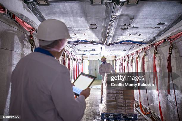 worker checking products into freezer truck of food factory with tablet - lossen stockfoto's en -beelden