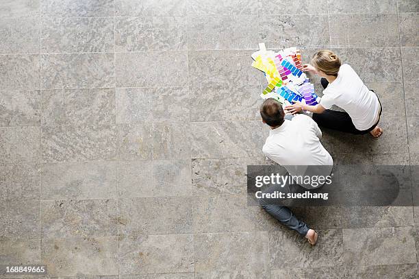 business people examining paint swatches - woman kneeling stockfoto's en -beelden