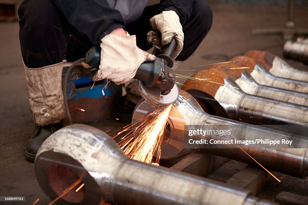 Worker using saw on metal in hydraulics factory