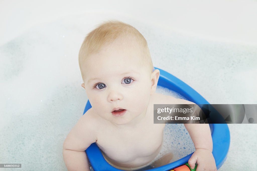 Baby girl sitting in seat in bath