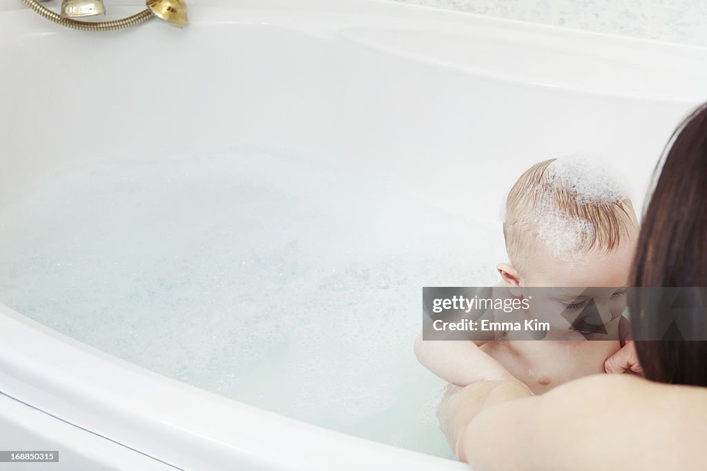 Mother washing baby girl in bubble bath