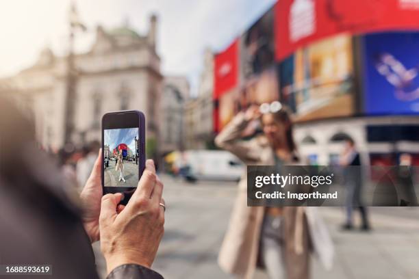 mother taking photos of teenage daughter in piccadilly circus in london, united kingdom - mobile billboard stock pictures, royalty-free photos & images