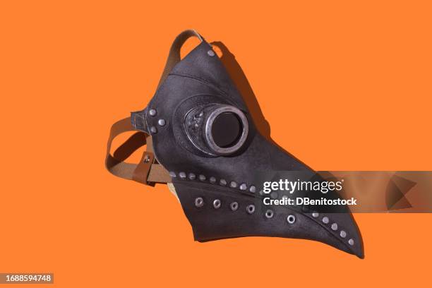 leather bubonic plague beak mask on orange halloween background. concept of costume, celebration, historical, middle ages, plague, medicine, pandemic, plague and doctor. - beak mask stock pictures, royalty-free photos & images