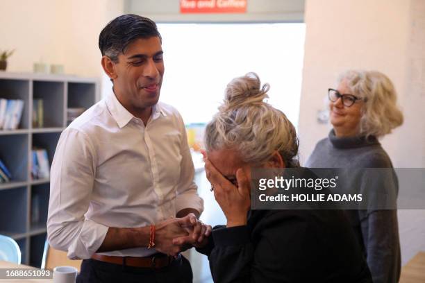 Britain's Prime Minster Rishi Sunak reacts as he talks with members of the community, a member of the community attending a breakfast club at Wormley...