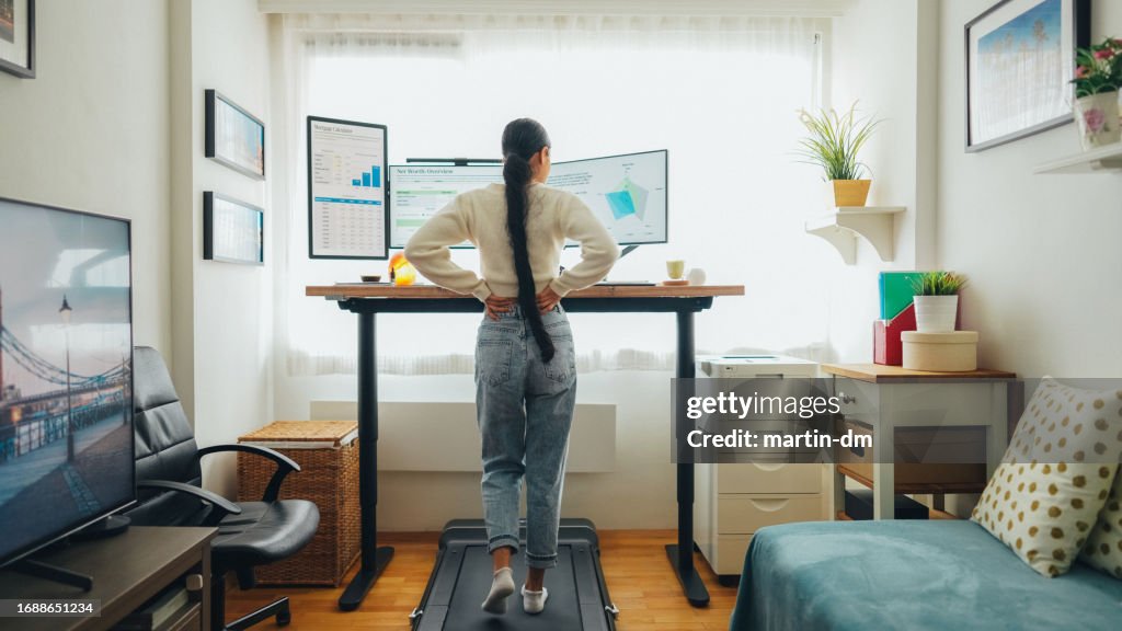 Woman with back pain working at standing desk home office