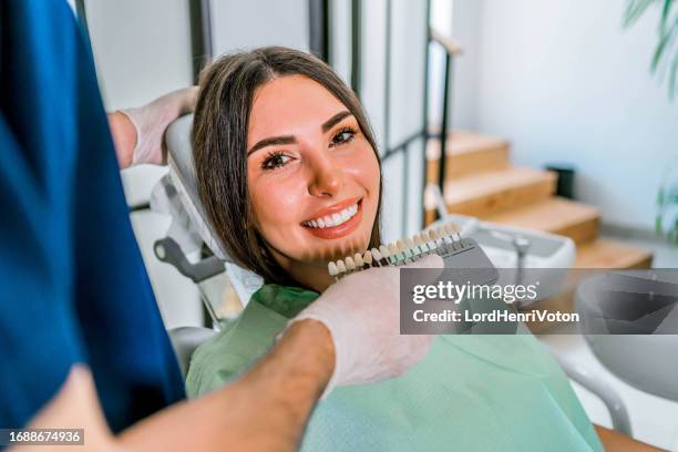 dentist comparing patient's teeth shade with samples - implante dentário imagens e fotografias de stock