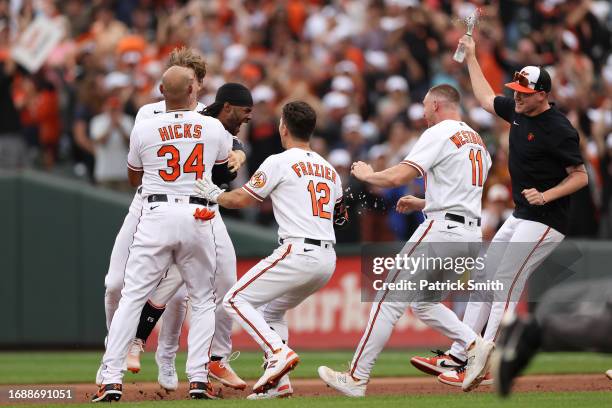 Cedric Mullins of the Baltimore Orioles celebrates with teammates after hitting a sacrifice RBI against the Tampa Bay Rays during the eleventh inning...