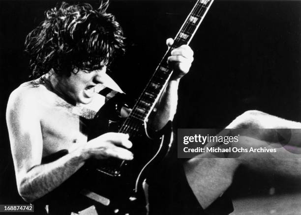 Guitarist Angus Young of the rock and roll group "AC/DC" sits down on stage as he plays a Gibson SG electric guitar in circa 1977.