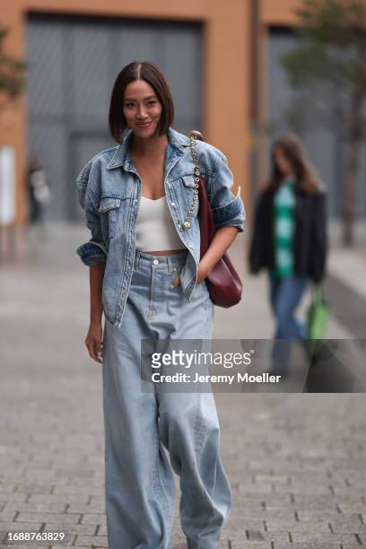 Tiffany Hsu is seen wearing a light blue jeans jacket, underneath a white cropped top, a wine-red leather bag from LOEWE and light blue high-waisted...