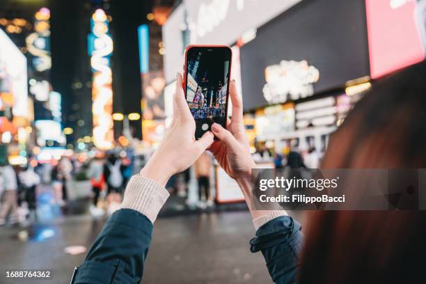 detail of the hands of a woman holding a smart phone in times square, new york city - mobile billboard stock pictures, royalty-free photos & images