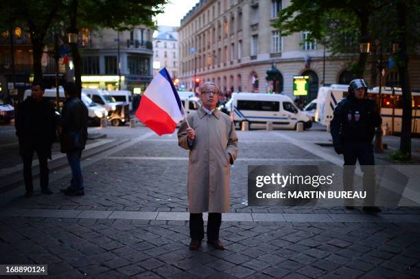 Man stands brandishing a French flag stands during a protest by anti gay-marriage movements on May 16, 2013 outside the Sorbonne University in Paris...