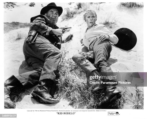 Broderick Crawford crouches next to Janet Leigh in a scene from the film 'Kid Rodelo', 1966.