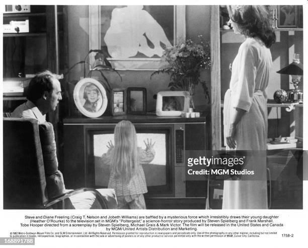 Craig T Nelson watches Heather O'Rourke approach the television with JoBeth Williams in a scene from the film 'Poltergeist', 1982.