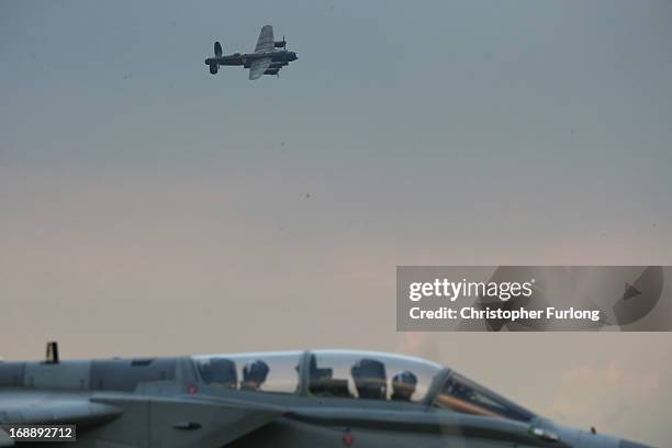 Lancaster Bomber 'The City of Lincoln' flys over a Tornado fighter aircraft from 617 Squadron as they take part in a Sunset Ceremony to mark the 70th...