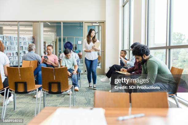 diverse people wait at free healthcare event held in library - medisch gebouw stockfoto's en -beelden