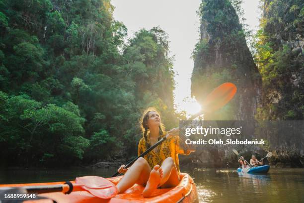 alegre mujer en kayak de mar entre formaciones kársticas y bosques de manglares en krabi - turismo ecológico fotografías e imágenes de stock