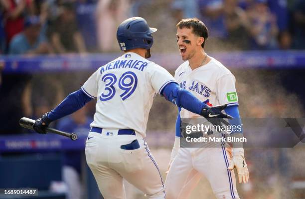 Cavan Biggio of Toronto Blue Jays celebrates with Kevin Kiermaier after sliding home to score the winning run to defeat the Boston Red Sox during the...