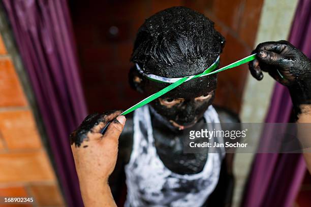 An assistant of Hermes Cifuentes, a Colombian spiritual healer, ties a ribbon around the head of Diana R., who claims to be possessed by spirits,...