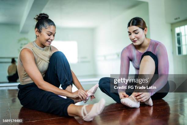 female friends talking and dressing on ballet shoes at the dance studio - hair bun stock pictures, royalty-free photos & images