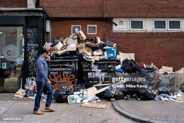 Man holds his nose as he passes refuse piled up in Whitechapel during four weeks of strike action by waste service workers in Tower Hamlets on 25th...