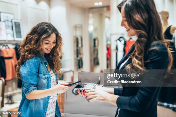 paying via smart phone at a clothing store - saleswoman stock pictures, royalty-free photos & images