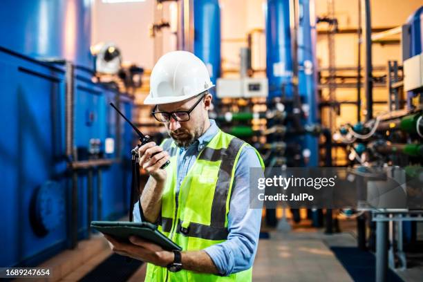 electrical engineer examining electric power station using digital tablet and walkie-talkie - gerador imagens e fotografias de stock