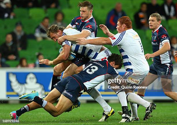 Andries Bekker of the Stormers is tackled by Mitch Inman and Jason Woodward of the Rebels during the round 14 Super Rugby match between the Rebels...