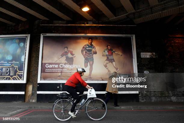 Cyclist rides her bike past a billboard advertisement for BT Group Plc's new sports television service BT Sport in London, U.K. On Friday, May 17,...