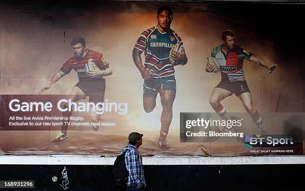 Pedestrian looks up at rugby players on a billboard advertisement for BT Group Plc's new sports television service BT Sport in London, U.K. On...