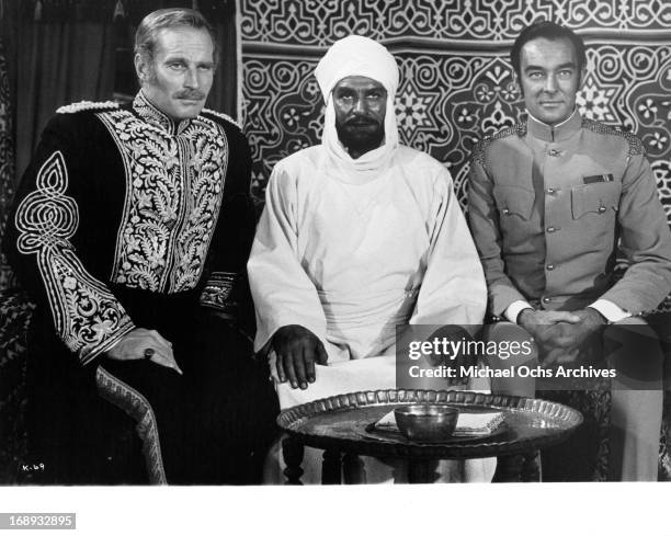 Charlton Heston, Richard Johnson and Laurence Olivier sitting side by side next to one an other in a scene from the film 'Khartoum', 1966.