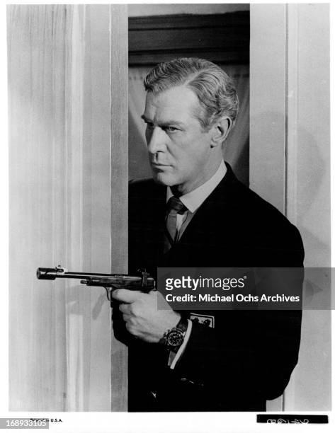 Edward Mulhares pointing a gun in a scene from the film 'Our Man Flint', 1966.