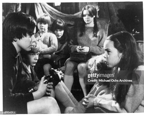 John Gugolka, Louis Sheldon Williams, Gustav Henry, Margaret Brooks, Mark Lester and Phoebe Nicholls listen to Pamela Franklin, seated with a bible,...