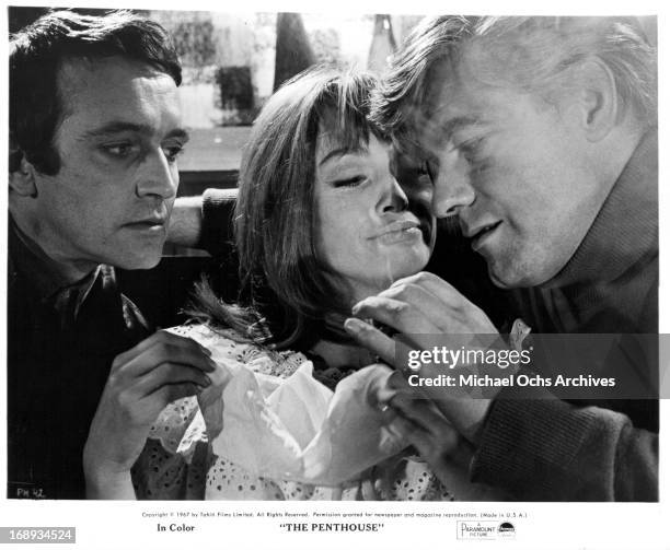 Tony Beckley and Norman Rodway have Suzy Kendall sandwiched between them as they hand feed her party favors in a scene from the film 'The Penthouse',...