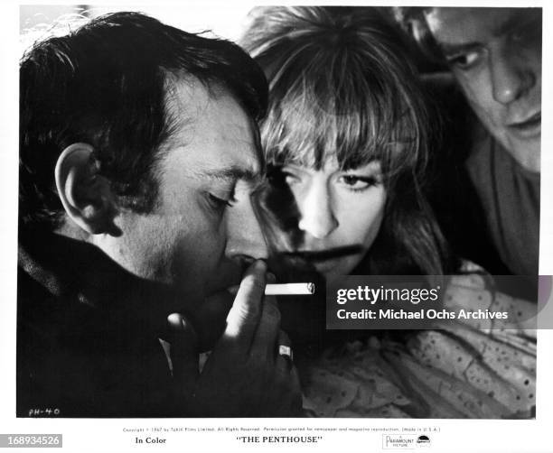 Tony Beckley and Norman Rodway have Suzy Kendall sandwiched between them as they hand feed her party favors in a scene from the film 'The Penthouse',...