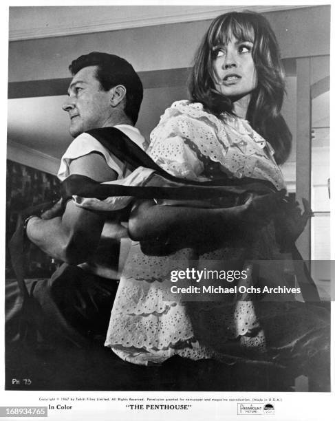 Suzy Kendall and Terence Morgan strapped together back to back in a scene from the film 'The Penthouse', 1967.