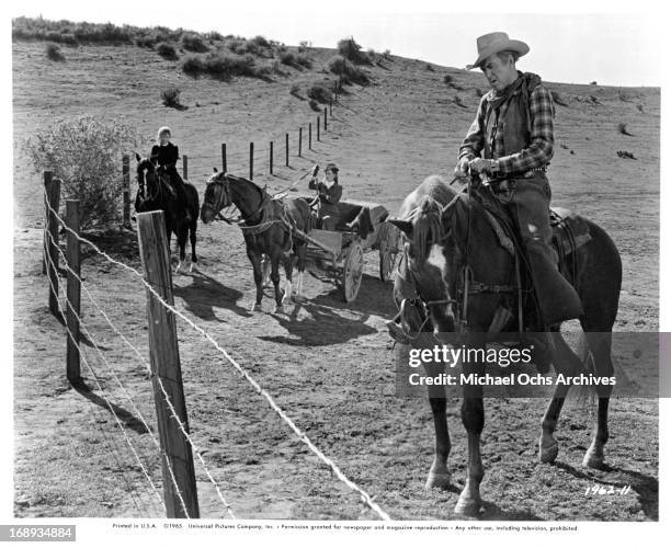 Maureen O'Hara watches James Stewart figure out how they are getting through the wire blocking their way to Texas in a scene from the film 'The Rare...