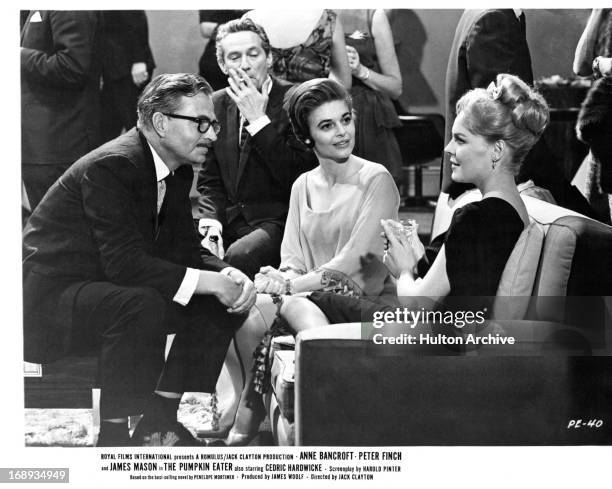 Peter Finch, Anne Bancroft, James Mason and Janine Gray sitting together at a cocktail lounge in a scene from the film 'The Pumpkin Eater', 1964.