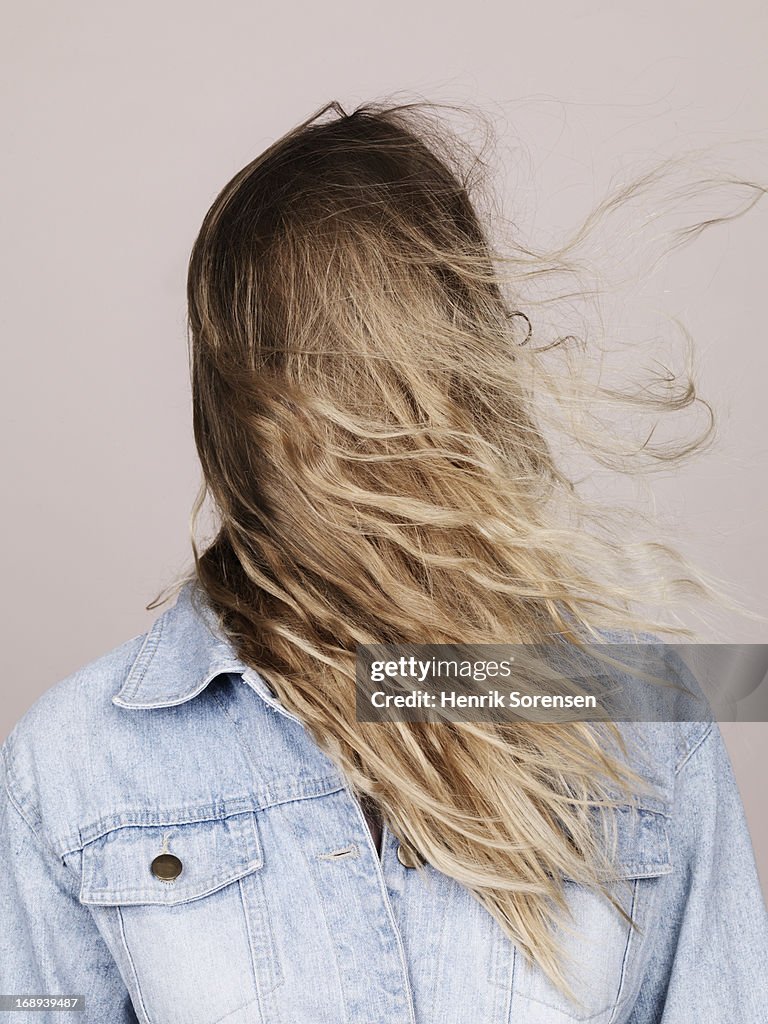 Woman with long hair blowing over her face.