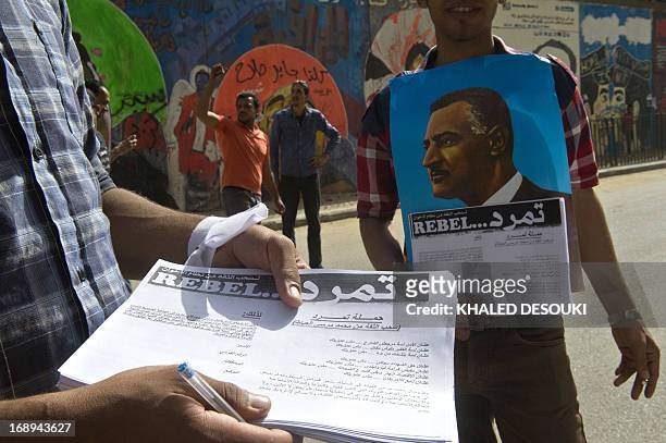 An Egyptian man distributes a sheet of Tamarod campaign try to collect signatures to demand the ouster of Egyptian President Mohamed Morsi and for...